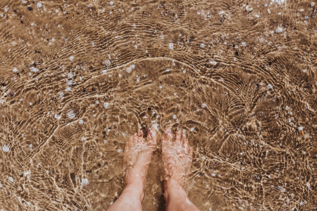 feet in ocean with sand