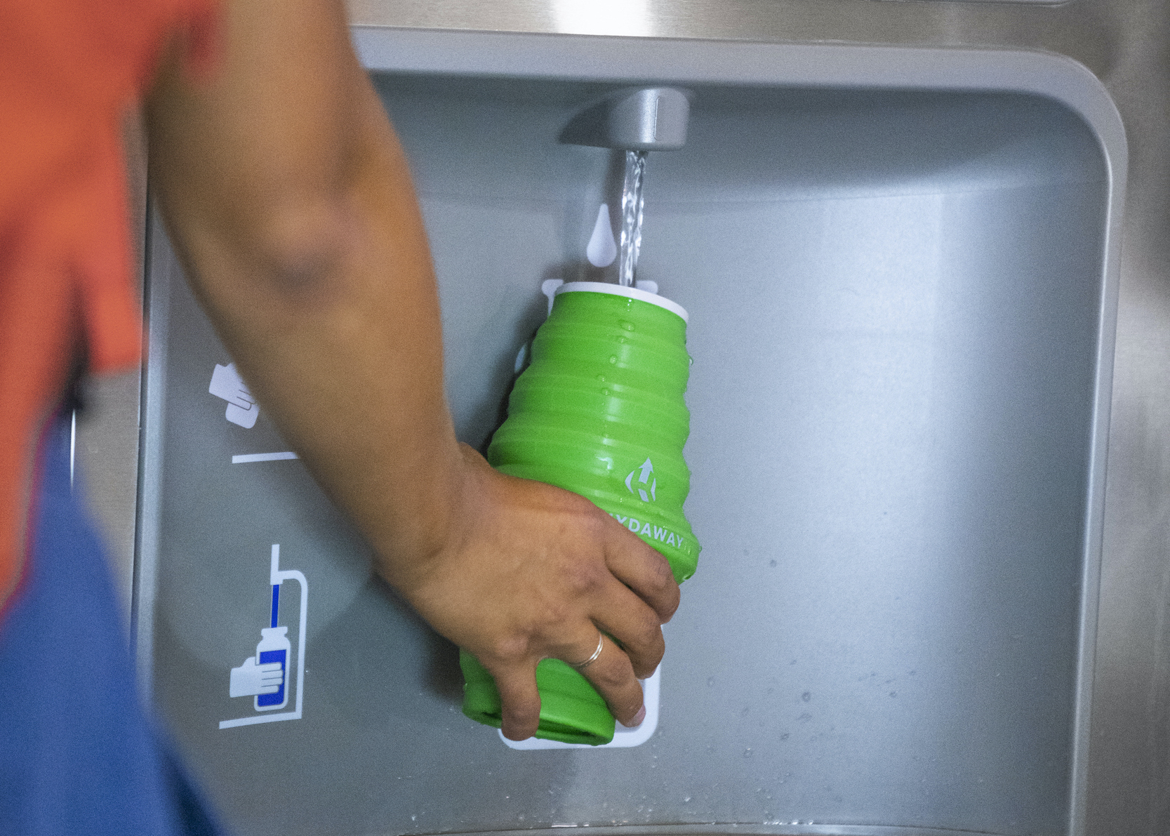 Filling a HYDAWAY Collapsible Travel Water Bottle at an airport filling station