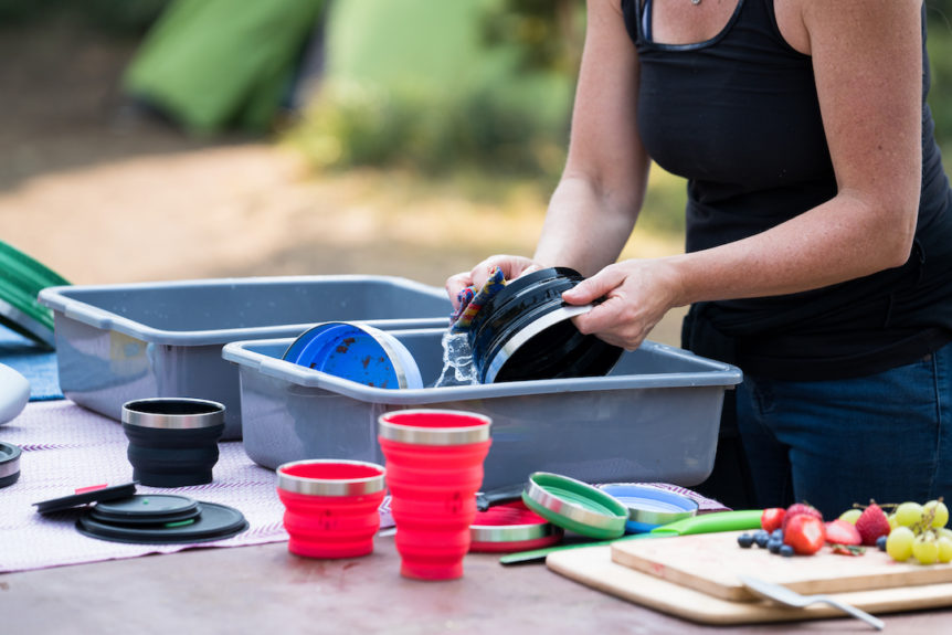 Woman washes HYDAWAY Collapsible Bowl, Pint, and Cup while camping