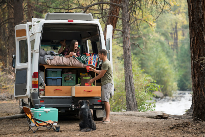 A couple camping in their camper van with dog, cooler, and HYDAWAY collapsible camp bowls